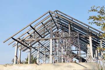 Steel roof structure. Detail of building structure with black steel roof trusses for new building in construction zone on blue sky background and selective focus