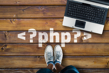 Wall Mural - man legs in sneakers standing next to laptop and php tag on wooden floor