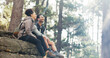 © Nicholas F/peopleimages.com - Nature, hiking and a couple relax on adventure trail in forest and sitting on a rock. Health, happy man and woman pointing at natural landscape while relaxing in woods with trees, fitness and freedom