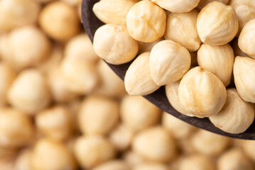 Poster - Close up of peeled hazelnuts in wooden spoon. Peeled hazelnuts with copy space