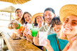 Happy multi ethnic friends cheering and drinking coloured cocktails in kiosk at beach - Young millennials and senior people having fun at summer weekend - Selfie lifestyle and party concept