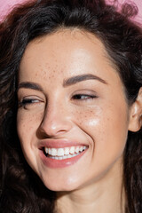 Wall Mural - Portrait of smiling woman with freckles looking away isolated on pink.