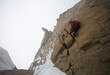 © Cavan Images - Man climbing cracks in storm wearing crampons.