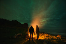 Standing Around An Campfire With Northern Lights - Aurora Borealis In The Sky Overhead, Unstad, VestvÃ¥gÃ¸y, Lofoten Islands, Norway