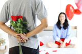Fototapeta  - Man hiding beautiful red rose bouquet behind back, ready to give Valentine flower present to lover girlfriend for celebration, couple make surprise, love and happiness. Happy Saint Valentine Day