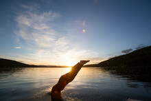 A Woman Dives In The Water From A Ski Boat On Whitefish Lake At Sunset In Whitefish, Montana.