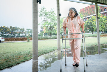 Wall Mural - Asian elderly woman patient who are doing physical therapy with a cane to support her walking, in path at hospital. to retirement age and health care concept.