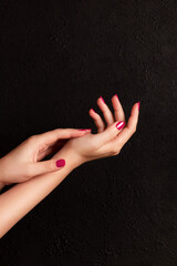 Wall Mural - Female hands with beautiful manicure - viva magenta, pink nails on dark black background. Nail, skin care concept
