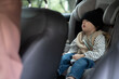 © Ananass - Little girl sleeping on the harness booster seat into a car. Security seat for children.