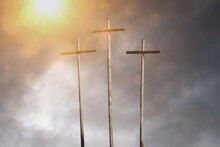 Three Crosses With Sun Shining Down Through Dark Cloudy Sky