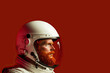 © Davidbenito - Close-up portrait of red-haired man with beard, wearing white astronaut suit and helmet, on red background, with copy space on the right. Image created with Artificial Intelligence.
