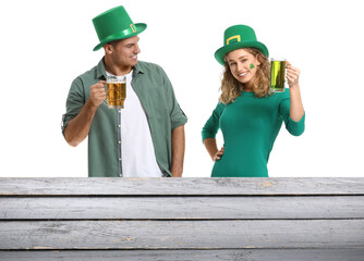 Poster - Happy young couple with beer near table on white background. St. Patrick's Day celebration