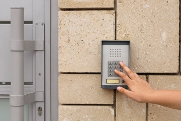 Child using modern intercom on stone wall outdoors, closeup