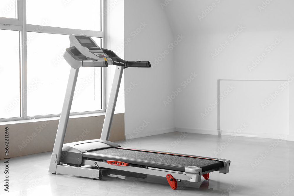Interior of room with modern treadmill near window