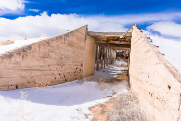 Wall Mural - Exterior tunnel entrance to deserted adobe Potato Bunker, San Luis Valley, Colorado, on sunny winter day with blue sky, clouds, and sunshine. Showing snow,  heavy adobe walls and beams.