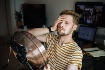 Fototapete - Heat wave during a summer, a man finds respite at his home balcony with the help of an electric fan. A man beats the summer heat wave by finding relief with an fan. The effect of global warming