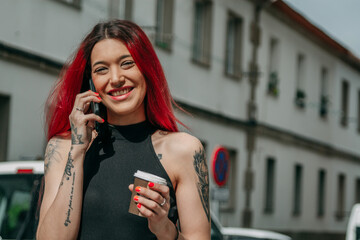 Wall Mural - urban redhead woman talking on mobile phone having a relaxed takeaway on the street