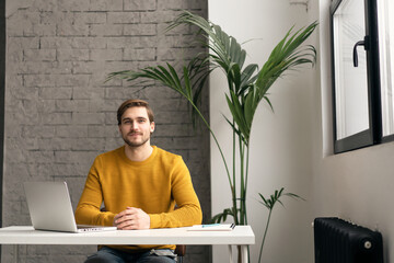 Portrait of young man sitting at his desk in the office