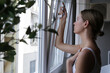 © triocean - Woman opening window at home in the morning to let fresh air in