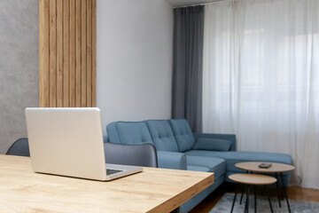 Laptop on the table in the living room of modern and cozy apartment