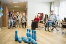 Girls Playing Bowling With Senior Women In Rest Home