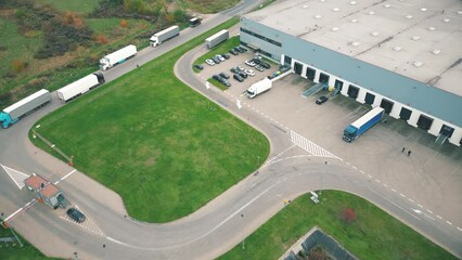 Wall Mural - Buildings of logistics center, warehouses near the highway, view from height, a large number of trucks in the parking lot near warehouse.