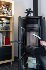 Woman cleaning pellet stove with accessoiries as vacuum cleaner or brush