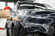 Worker applies a protective film or anti-gravity protective coating to the car headlight. Details of the car.