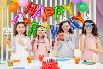 Happy children with photo booth props at birthday party.