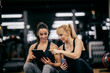 © dusanpetkovic1 - A happy sportswoman is pointing at the tablet while her female personal trainer is showing her progress in a gym.