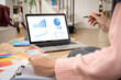 © krumanop - Woman using computer laptop at modern home. Project stats financial data sales charts on laptop after sale products, close up view over shoulder.