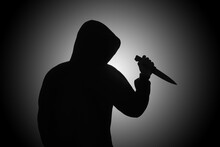 Mysterious Man Wearing Black Hoodie Holding A Knife To Stab Someone. Crimes And Criminality Concept