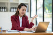 © crizzystudio - Asian businesswoman clicking details on laptop computer analyzing data checking accuracy of financial income happily in office management concept management.