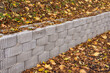 A retaining wall made of concrete elements protects the roadway and pavement from sliding down the slope. Autumn.