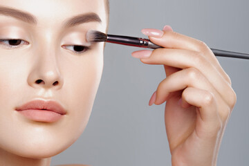 Wall Mural - Young woman applies eye shadow with brush