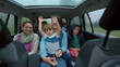 © Marco - Happy people inside car backseat waving hands laughing and smiling together. Family traveling in vehicle interior on road. Authentic happiness concept