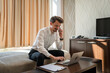 © Miljan Živković - One man adult Caucasian male work from hotel room make a call on phone