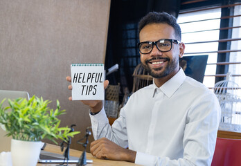 Wall Mural - The words HELPFUL TIPS written on the notebook. Notebook in hand on office background.