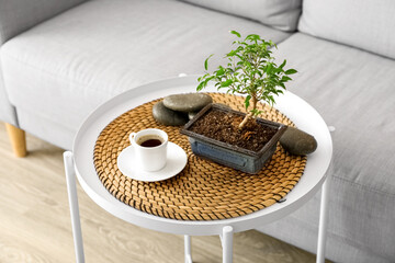Wall Mural - Bonsai tree, cup of coffee and spa stones on table in living room