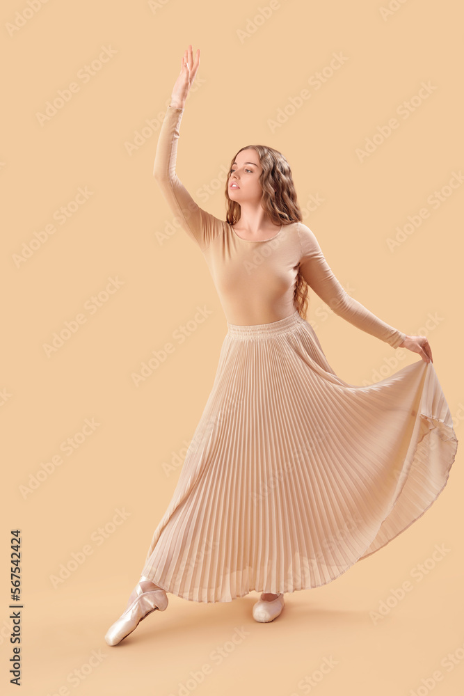 Young ballerina dancing on beige background