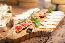 Sliced Hard Cheese Served On Wooden Boards With Fresh Aromatic Rosemary, Basil And Sweet Figs. Degustation At Spanish Goat Farm