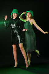 Young women in hats on dark background. St. Patrick's Day celebration