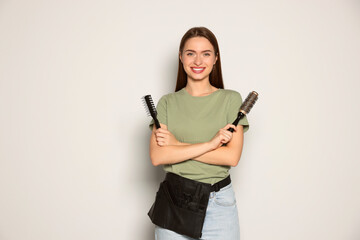 Poster - Portrait of happy hairdresser with brushes on light background