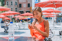 Woman Using Phone Drinking Water Sitting A Table In New York City Street In Gansevoort Plaza, A Public Space In The Meatpacking District Of NYC. Girl In Manhattan, USA. Happy Young Adult Lifestyle