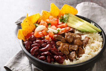 Wall Mural - Chifrijo is a delicious traditional Costa Rican dish made with red beans and pork, accompanied by pico de gallo and rice closeup on the plate on the table. Horizontal