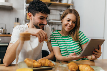 Canvas Print - Young couple reading news in the kitchen