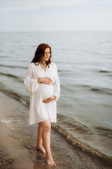 Wall Mural - pregnant girl with brown hair on the seashore