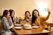 © Katcha - Young people sitting on the couch to smiling with enjoying and using smartphone to selfie together while dinner and celebrating in new year party at home