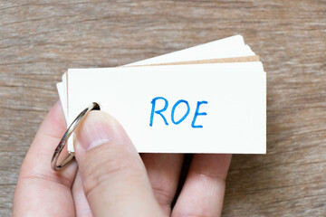 Wall Mural - Hand hold flash card with handwriting in word ROE (Abbreviation of Return on equity) on wood background