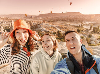 Wall Mural - Group of happy students friends taking selfie photos for social networks in Cappadocia, Turkey. Travel and influencer concept